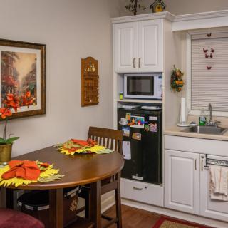 A cozy kitchen with a small dining table set for two, adorned with decorative flowers and a microwave nearby.