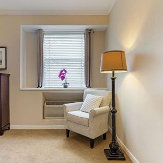 A cozy corner featuring an armchair and a floor lamp by the window.