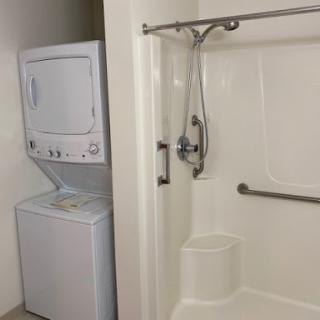 A compact laundry area with a washer and dryer next to a shower.