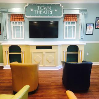 A cozy theater-themed seating area with a large TV screen and comfortable chairs.