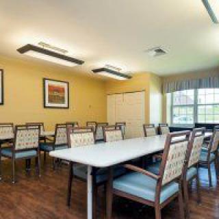 A well-lit dining room with several tables and chairs, featuring framed artwork on the walls.