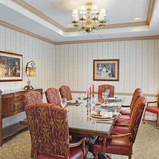A formal dining room with a large table, upholstered chairs, and elegant decor.