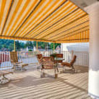 A cozy outdoor patio with a striped awning providing shade over a seating area.