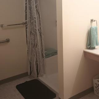 A clean and functional bathroom featuring a shower area, towel rack, and decorative towels.