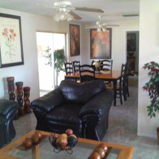 A cozy living room with black leather furniture and a dining area adorned with artwork.