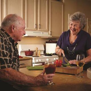 An elderly couple enjoying each other's company while preparing a meal in the kitchen.