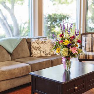 A cozy living room featuring a comfortable sofa, a stylish coffee table, and a vibrant bouquet of flowers.