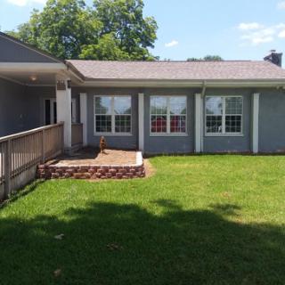 A charming view of the house's backyard with a patio and lush green grass.