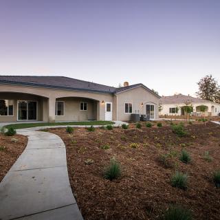 A modern single-story house with a landscaped yard and a curved pathway.