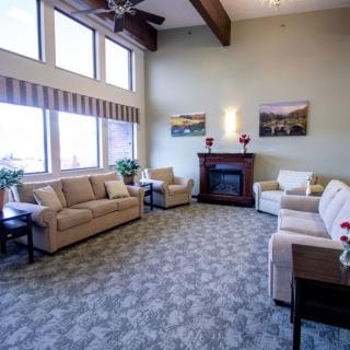 A cozy living room with sofas, a fireplace, and large windows.