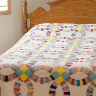 A colorful patchwork quilt draped over a wooden bed.