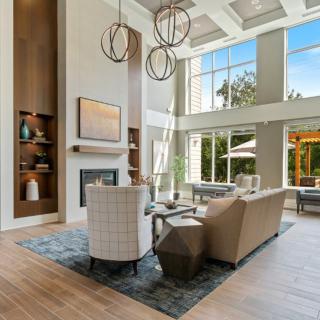 A modern living room with high ceilings and large windows, featuring contemporary furniture and a fireplace.