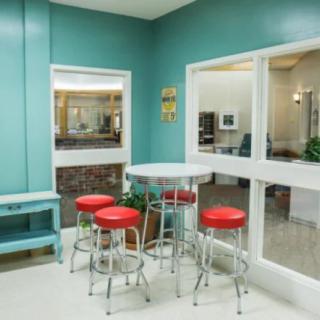 A retro-style diner with teal walls and red barstools.