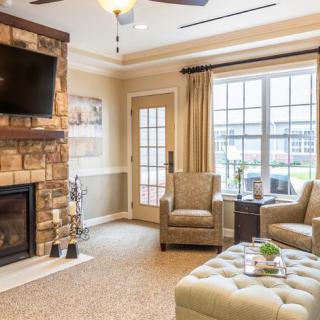 A cozy living room features a stone fireplace, flat-screen TV, and plush seating.