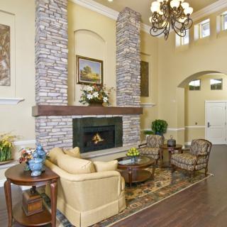 A cozy living room featuring a stone fireplace, elegant furniture, and a chandelier.