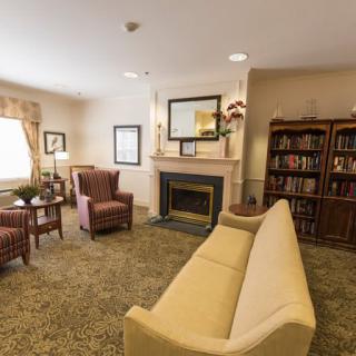A cozy living room featuring a sofa, armchairs, fireplace, and bookshelf.