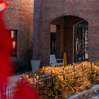 A cozy entrance surrounded by autumn foliage and brick architecture.