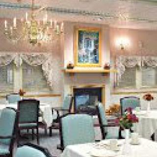 An elegant dining room featuring a chandelier and a fireplace with neatly arranged tables and chairs.