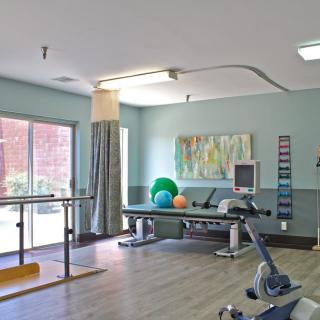 A spacious physical therapy room equipped with various exercise tools and apparatuses for rehabilitation.