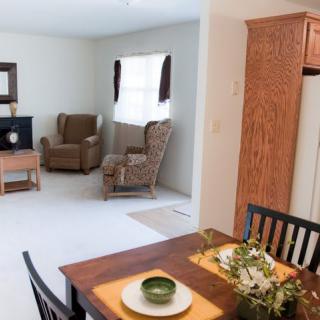 A cozy living space featuring a comfortable armchair, a television, and a dining area with table settings.
