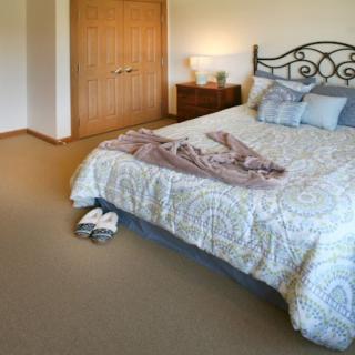 A cozy bedroom with a neatly made bed and soft lighting.