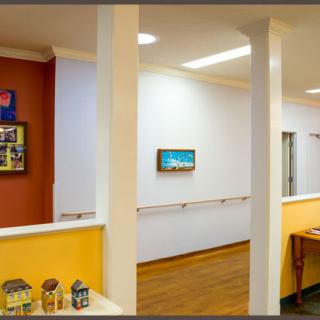 A brightly decorated hallway with colorful walls, artwork, and a wooden floor.
