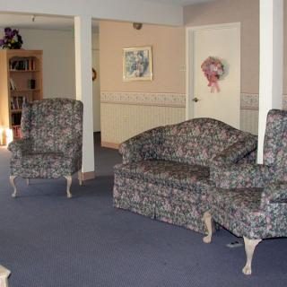 A living room with a floral-patterned sofa and armchair, featuring carpet flooring and wall decorations.