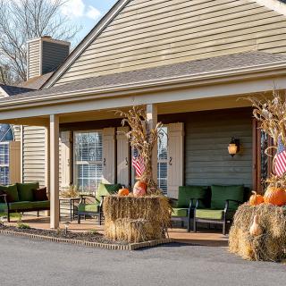 A cozy porch decorated with pumpkins and hay bales for the autumn season.