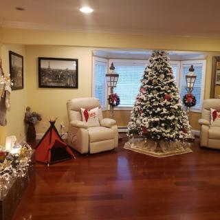 A cozy living room decorated for Christmas with a beautifully adorned tree and festive touches throughout.