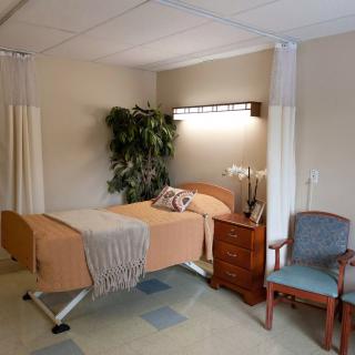 A hospital room featuring a single patient bed and accompanying furniture.