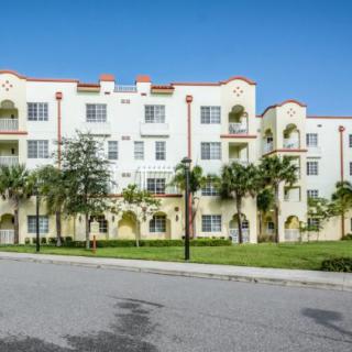A sunny day view of a residential apartment building with palm trees in front.