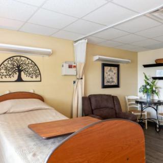 A hospital room with a patient bed and seating area.