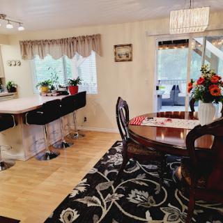 A cozy and well-decorated dining area adjacent to a kitchen, featuring elegant furniture and vibrant plants.