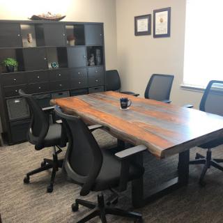 A modern conference room featuring a large wooden table and ergonomic chairs, ready for meetings.