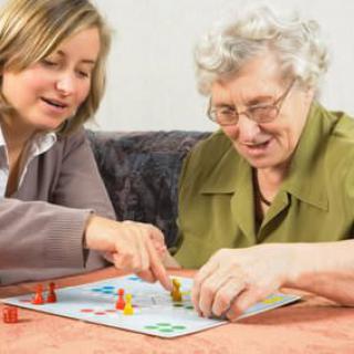 An elderly woman and a younger woman enjoying a board game together indoors.