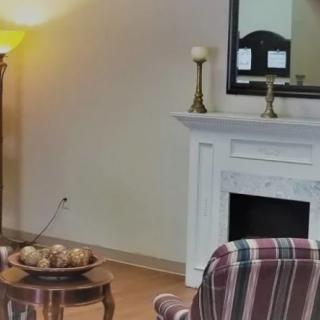 A cozy living room featuring a white fireplace, a mirror, and a striped chair.