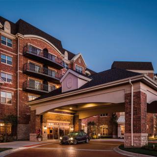 A cozy hotel entrance with a car parked under the canopy during the evening.