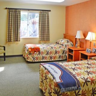 A cozy hotel room with twin beds and a window view.