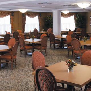 A spacious indoor dining area with multiple tables and chairs set up, featuring elegant decor and large windows.