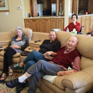 A family gathering in the living room, enjoying each other's company on the couch.