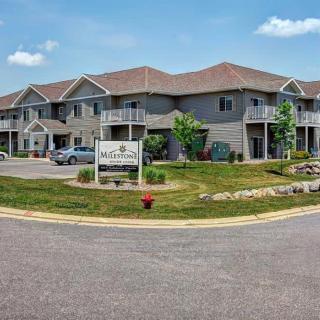 A modern apartment building with balconies and a well-maintained lawn under a clear blue sky.