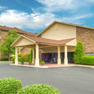A hotel entrance with a covered driveway and surrounding greenery.