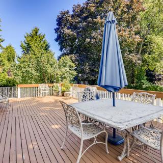 A spacious outdoor deck with a table, chairs, and an umbrella, surrounded by lush trees.