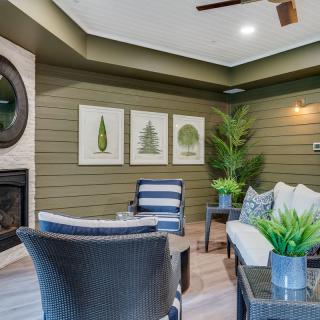 A modern living room featuring a fireplace, artwork, and comfortable seating with plants adding a touch of greenery.