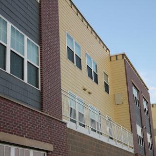 A close-up view of the exterior of a modern residential building featuring varied materials and window designs.