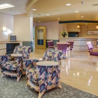 A hospital waiting room with comfortable chairs and a reception desk.