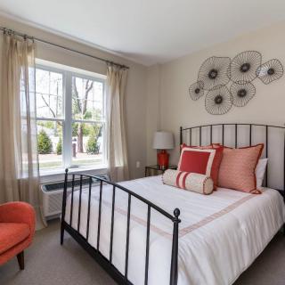 A modern bedroom featuring a metal-frame bed with decorative pillows and natural light streaming through a large window.