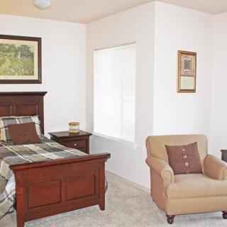 A cozy bedroom with a wooden bed, armchair, and decorative elements.