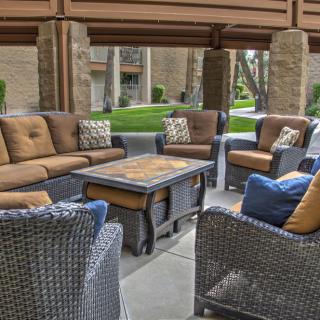 A cozy outdoor seating area with cushioned wicker furniture under a covered patio.