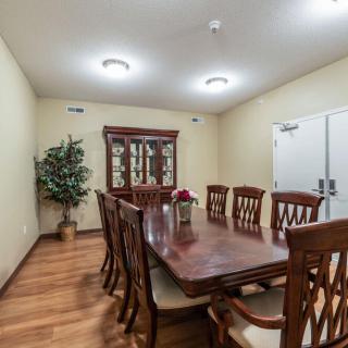 A dining room with a wooden table and chairs, featuring a cabinet and indoor plant.
